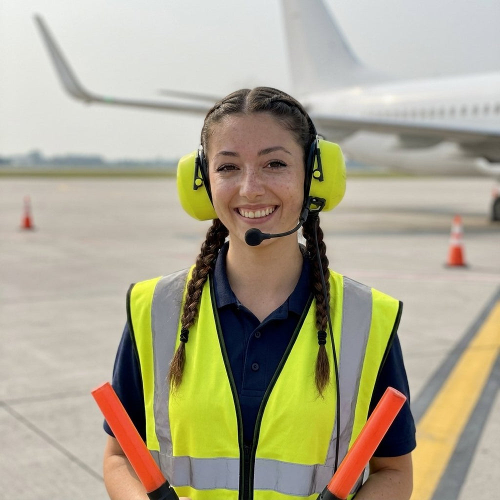 Ramp agent in a hi-vis vest and ear defenders on the apron